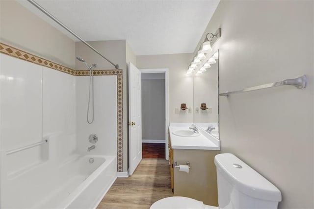 full bathroom featuring toilet, vanity, shower / tub combination, wood finished floors, and a textured ceiling