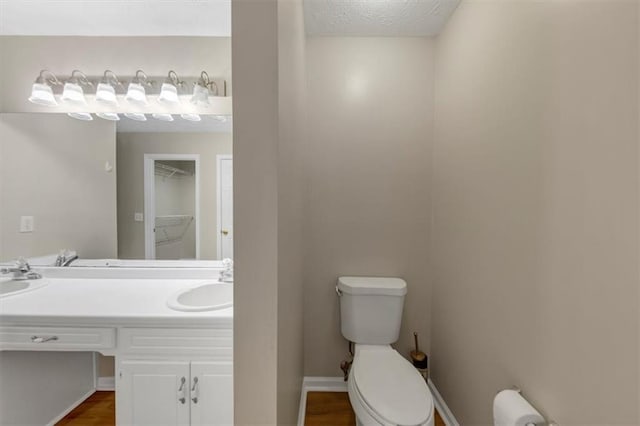 bathroom with a sink, a textured ceiling, toilet, and double vanity