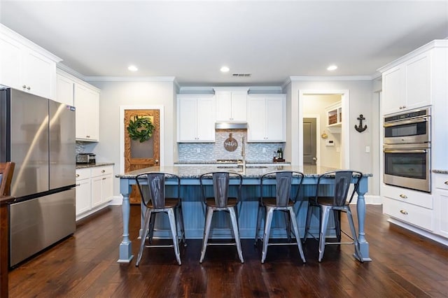 kitchen featuring a kitchen island with sink, stainless steel appliances, white cabinets, and stone counters