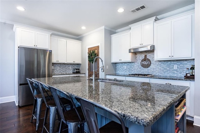 kitchen featuring stainless steel appliances, a center island with sink, white cabinets, and dark hardwood / wood-style flooring