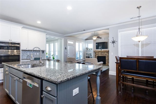 kitchen featuring sink, a center island with sink, appliances with stainless steel finishes, pendant lighting, and white cabinets