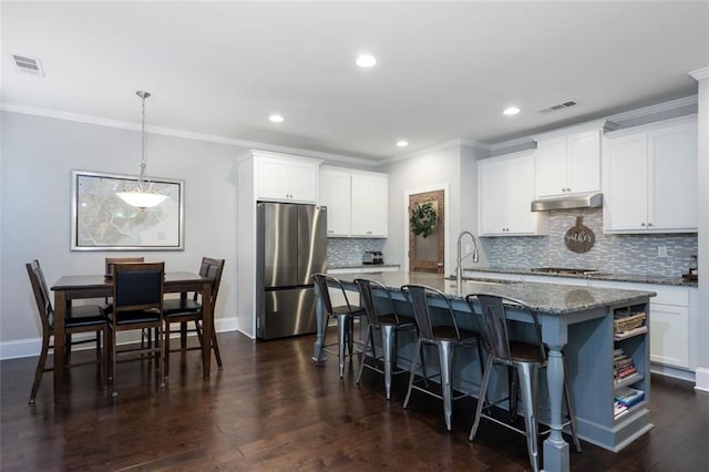 kitchen with sink, white cabinetry, a center island with sink, dark stone countertops, and stainless steel appliances