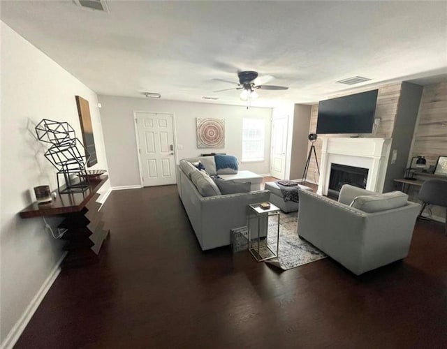 living room with dark wood-style flooring, visible vents, a fireplace, and baseboards