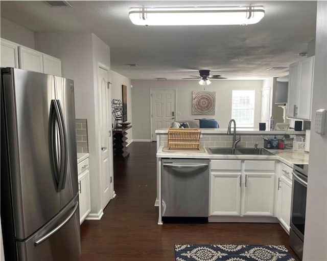 kitchen featuring a peninsula, tasteful backsplash, appliances with stainless steel finishes, and dark wood finished floors