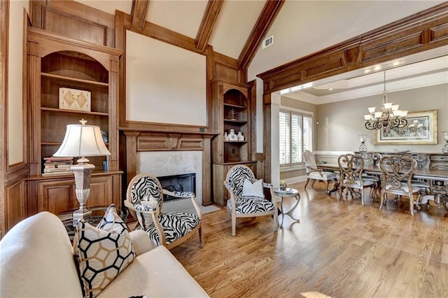 8340 Royal Melbourne Way, Duluth, GA 30097 - living room with built in shelves, wood finished floors, a high end fireplace, a chandelier, and beamed ceiling