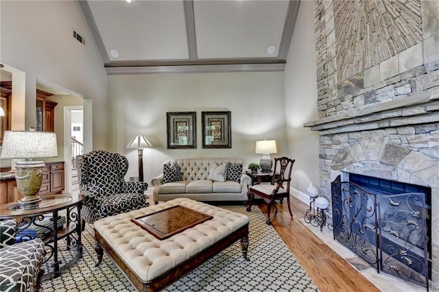 8340 Royal Melbourne Way, Duluth, GA 30097 - living area featuring crown molding, high vaulted ceiling, light wood-style flooring, a stone fireplace, and baseboards