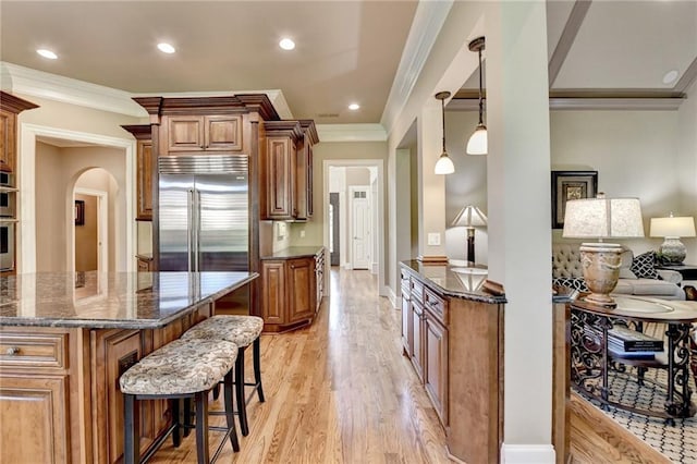 8340 Royal Melbourne Way, Duluth, GA 30097 - kitchen with appliances with stainless steel finishes, a kitchen breakfast bar, ornamental molding, light wood-type flooring, and dark stone counters