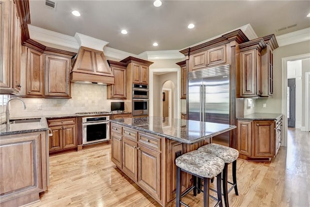 8340 Royal Melbourne Way, Duluth, GA 30097 - kitchen with a sink, a kitchen island, crown molding, custom range hood, and dark stone countertops