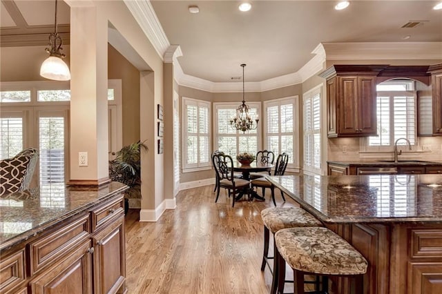8340 Royal Melbourne Way, Duluth, GA 30097 - kitchen featuring a sink, dark stone counters, a breakfast bar, recessed lighting, and light wood finished floors