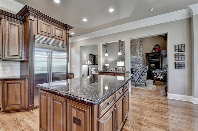 8340 Royal Melbourne Way, Duluth, GA 30097 - kitchen with built in fridge, light wood finished floors, dark stone counters, a fireplace, and a center island
