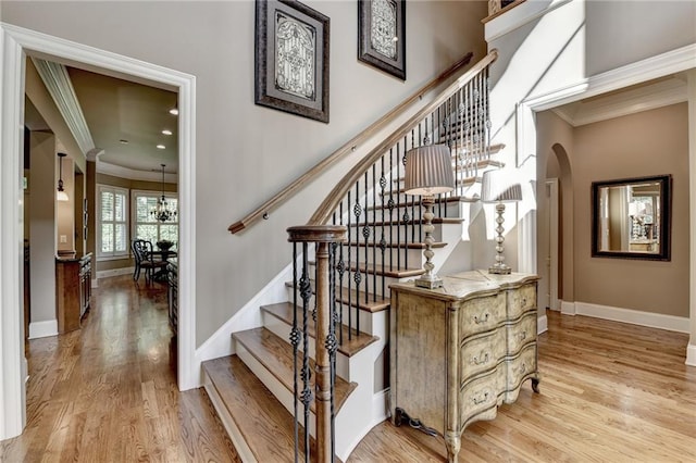 8340 Royal Melbourne Way, Duluth, GA 30097 - stairway with crown molding, wood finished floors, baseboards, arched walkways, and a chandelier