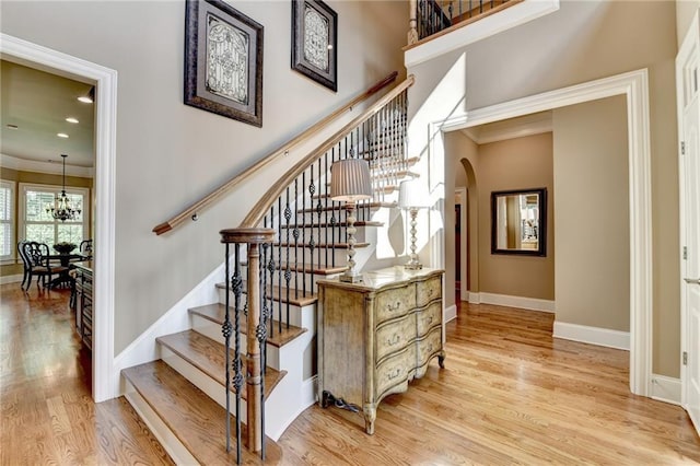 8340 Royal Melbourne Way, Duluth, GA 30097 - stairway with arched walkways, a chandelier, wood finished floors, baseboards, and crown molding