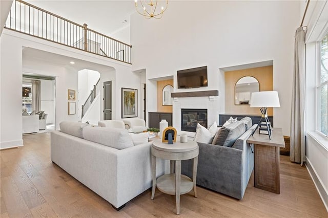 9110 Greenway Ct, Gainesville, GA 30506 - living room with light wood-type flooring, a glass covered fireplace, baseboards, a high ceiling, and stairs