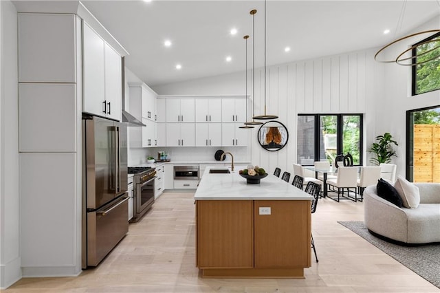 6178 Lake Lanier Height Rd, Buford, GA 30518 - kitchen with high end appliances, under cabinet range hood, an island with sink, white cabinetry, and pendant lighting