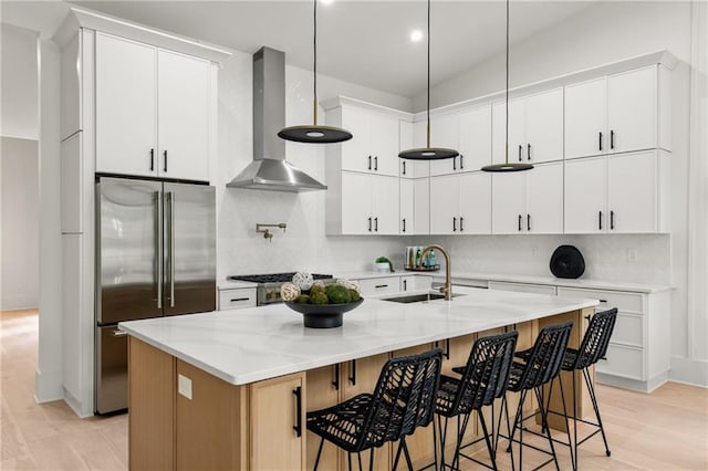 6178 Lake Lanier Height Rd, Buford, GA 30518 - kitchen featuring wall chimney exhaust hood, high end fridge, light wood-style floors, decorative backsplash, and a kitchen island with sink