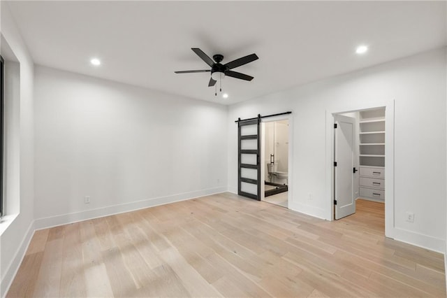 6178 Lake Lanier Height Rd, Buford, GA 30518 - unfurnished bedroom with a barn door, light wood-style floors, recessed lighting, a walk in closet, and connected bathroom