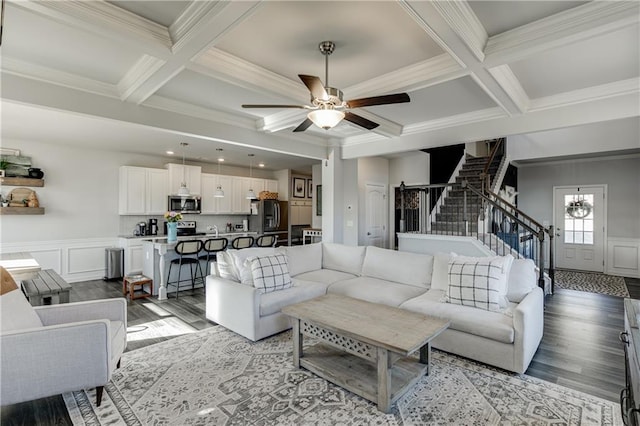 living area featuring coffered ceiling, light wood-style flooring, stairs, beam ceiling, and a decorative wall