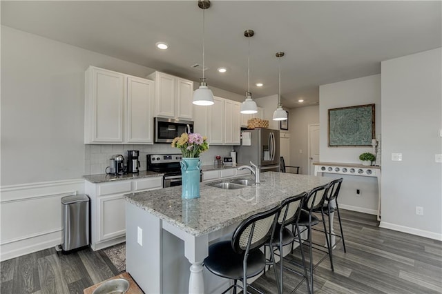 kitchen with stainless steel appliances, a sink, dark wood-style floors, white cabinetry, and recessed lighting