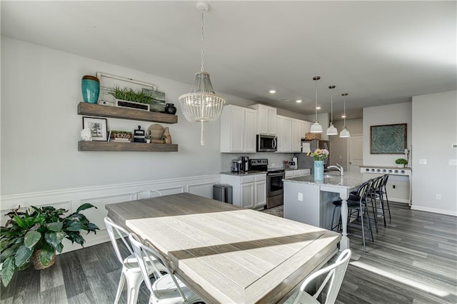 dining room featuring dark wood-style flooring, a chandelier, recessed lighting, wainscoting, and baseboards
