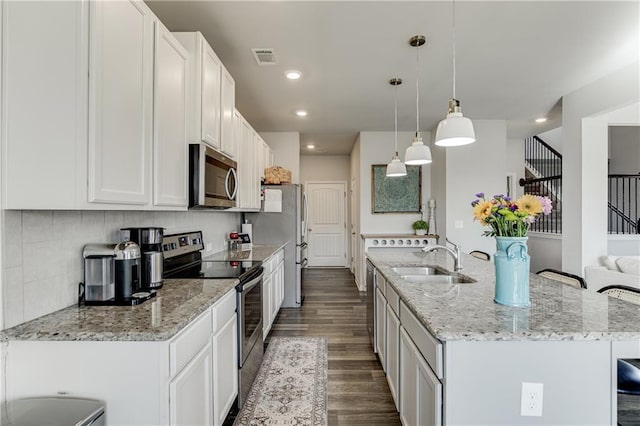 kitchen with stainless steel appliances, a sink, an island with sink, dark wood-type flooring, and white cabinetry