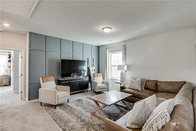 living room with attic access, light colored carpet, and baseboards