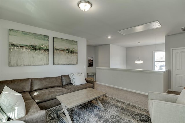 living room featuring attic access, carpet flooring, and baseboards