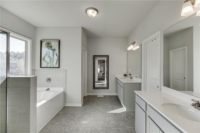 bathroom featuring two vanities, a bath, and baseboards