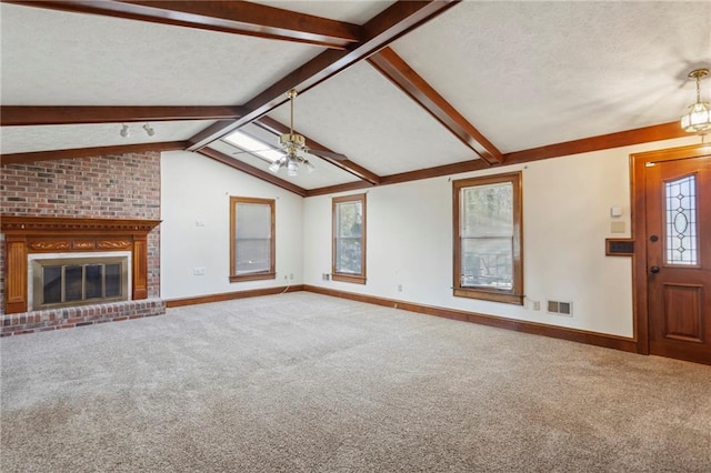 unfurnished living room featuring carpet, lofted ceiling with beams, a brick fireplace, ceiling fan, and a textured ceiling