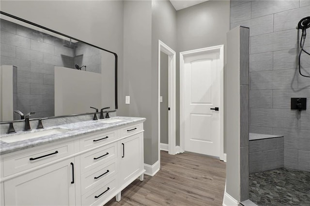 bathroom with hardwood / wood-style flooring, tiled shower, and vanity