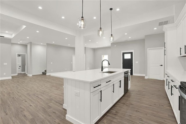 kitchen featuring white cabinetry, sink, a center island with sink, and decorative light fixtures