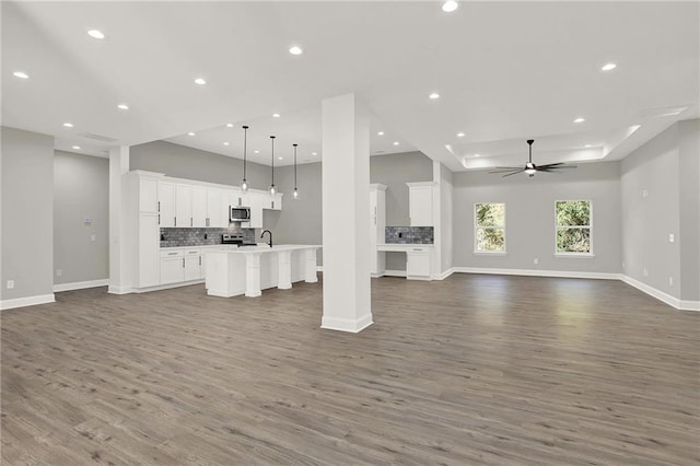 unfurnished living room featuring hardwood / wood-style flooring, sink, and ceiling fan