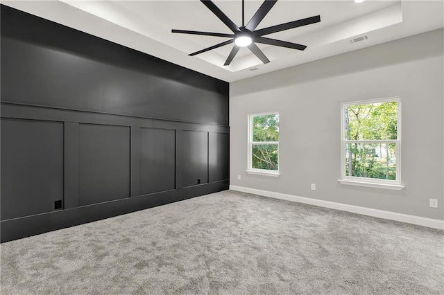 unfurnished bedroom featuring a raised ceiling, carpet flooring, and ceiling fan