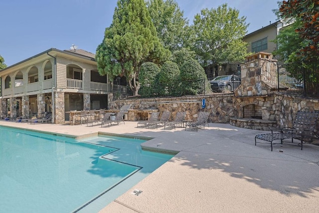 view of pool featuring a patio area and an outdoor stone fireplace