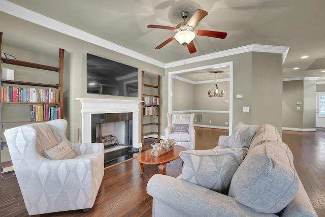 living room with dark hardwood / wood-style floors, ceiling fan with notable chandelier, crown molding, and a tiled fireplace