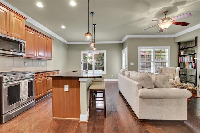 kitchen with appliances with stainless steel finishes, ceiling fan, a center island with sink, dark hardwood / wood-style floors, and sink