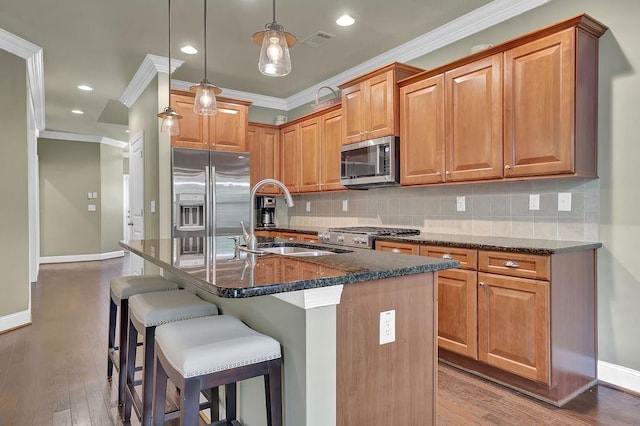 kitchen with pendant lighting, sink, wood-type flooring, a kitchen island with sink, and stainless steel appliances