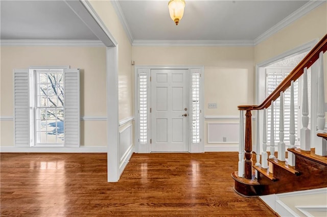 foyer with a decorative wall, ornamental molding, stairs, and wood finished floors