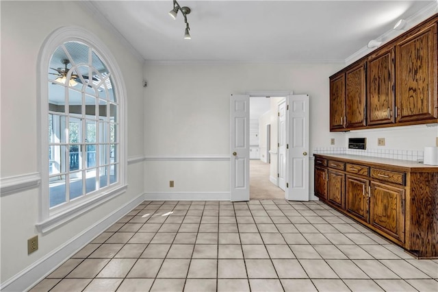 kitchen with crown molding, a ceiling fan, baseboards, and light countertops