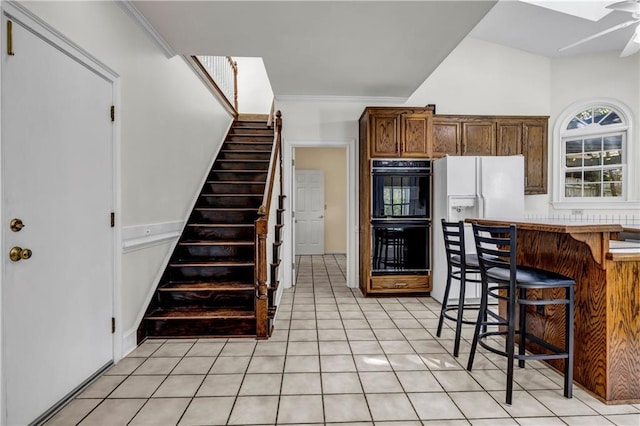 kitchen featuring crown molding, a kitchen breakfast bar, light tile patterned floors, and dobule oven black