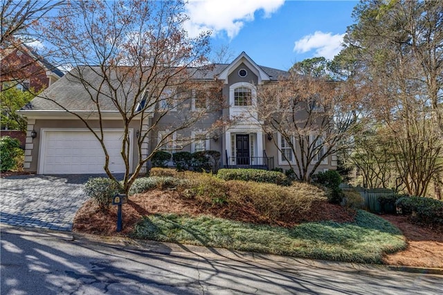 view of front facade with decorative driveway, fence, a garage, and stucco siding