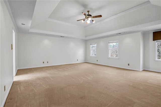 empty room featuring baseboards, ornamental molding, ceiling fan, a raised ceiling, and light colored carpet