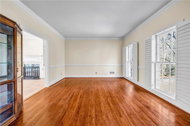 spare room featuring visible vents, crown molding, baseboards, and wood finished floors