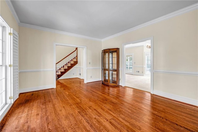 spare room featuring wood finished floors, stairs, baseboards, and ornamental molding