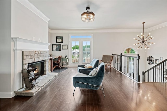 living area featuring french doors, an inviting chandelier, ornamental molding, dark hardwood / wood-style flooring, and a fireplace