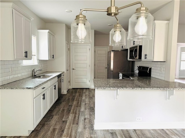 kitchen with a sink, white cabinetry, light stone countertops, and stainless steel appliances