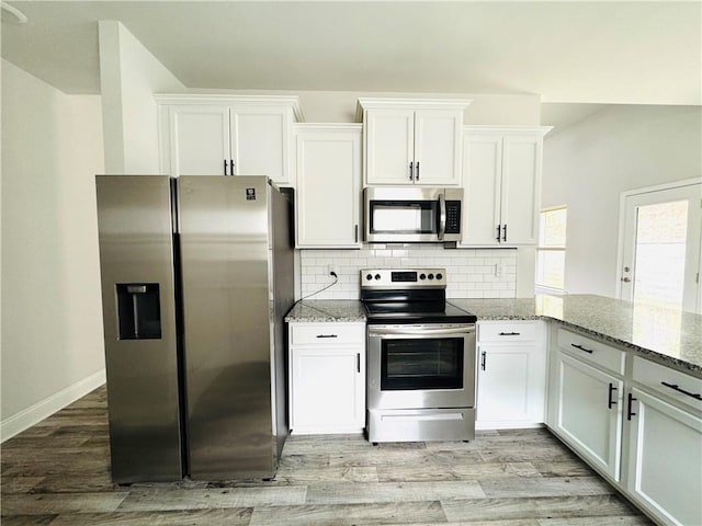kitchen featuring light stone counters, white cabinets, stainless steel appliances, and light wood-type flooring