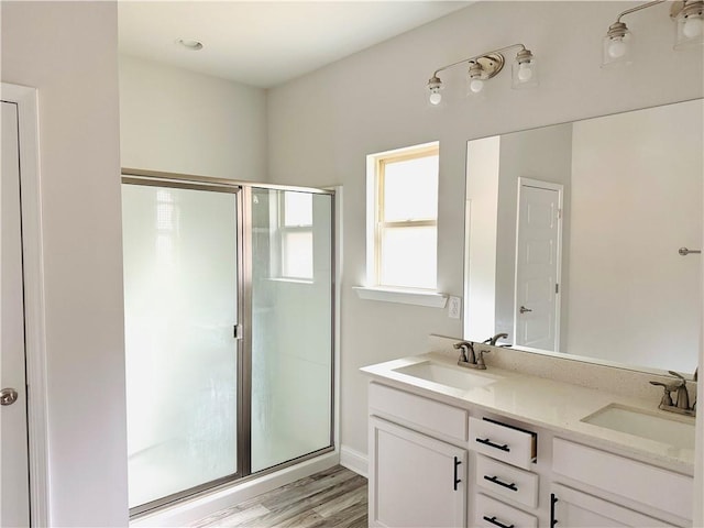 bathroom featuring a sink, double vanity, a shower stall, and wood finished floors