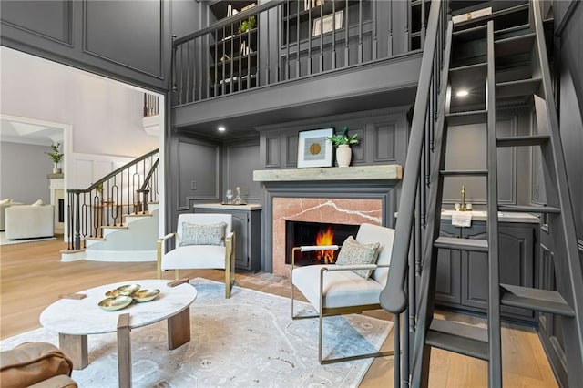 12995 Bucksport Dr, Roswell, GA 30075 - living room featuring stairs, light wood-type flooring, a high end fireplace, a decorative wall, and a high ceiling