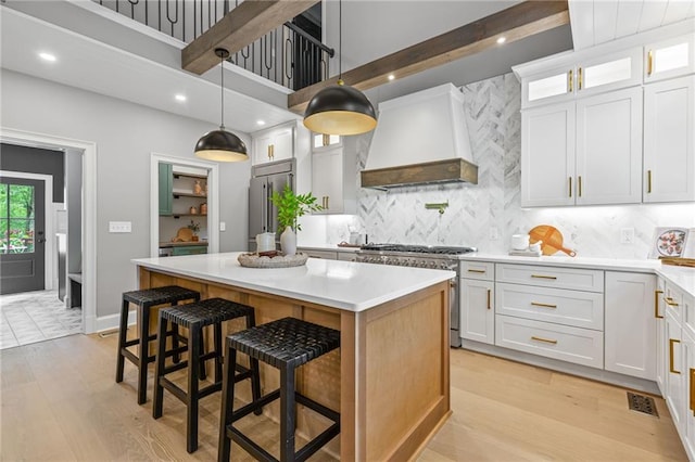 12995 Bucksport Dr, Roswell, GA 30075 - kitchen featuring custom range hood, high quality appliances, a center island, light wood-style floors, and light countertops