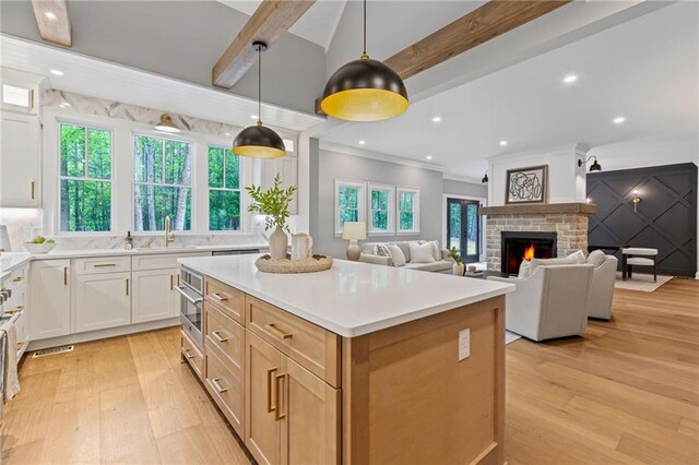 12995 Bucksport Dr, Roswell, GA 30075 - kitchen with light wood finished floors, beam ceiling, a sink, plenty of natural light, and ornamental molding